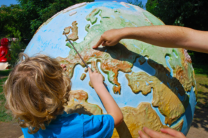 child pointing out a country on a globe to an adult