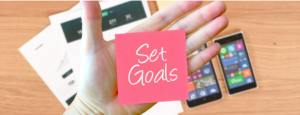 "Set Goals" written on a sticky note attached to a person's hand
