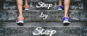 people going up steps, with the words "step by step" on the steps