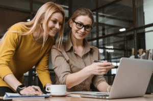 two women pointing to information on a laptop screen