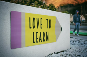 picture of a pencil on a wall; the pencil says "love to learn"