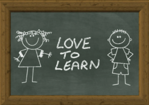 two stick figures drawn on a blackboard, with the phrase "love to learn"