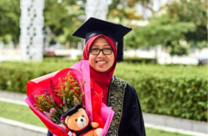 graduate in regalia, holding a bouquet of flowers