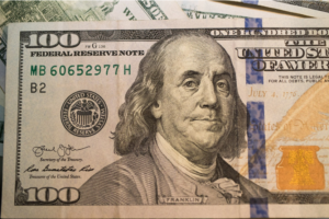 $100 bill laid on top of other U.S. currency