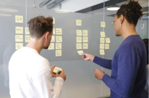 people putting sticky notes on a board