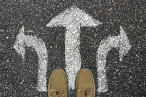 person standing on pavement with three arrows going in different directions