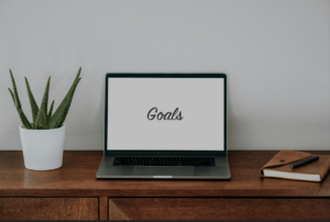 open laptop on a desk; laptop screen says "goals"