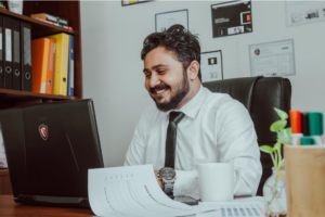 accountant at desk with computer and certificates on wall behind