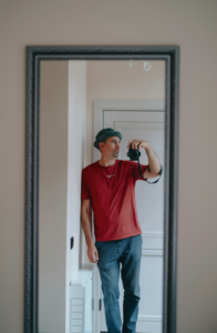 man holding camera to take a self-portrait using a full-length mirror