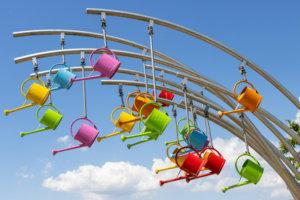 different colored watering cans hanging from steel supports; together they create a coherent work of art