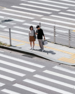 two people at crosswalk looking at directions on phone