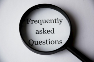 hand holding a magnifying glass over the words "Frequently asked Questions"