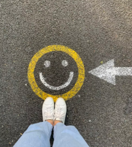 person standing on pavement; pavement shows an arrow pointing to a smiley face