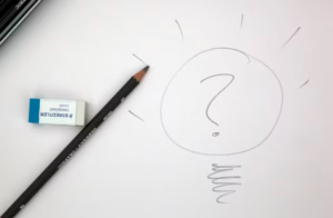 paper and pencil, with lightbulb and question mark drawn on the paper