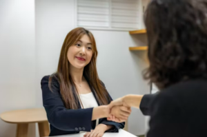 two business people sitting at a table, shaking hands