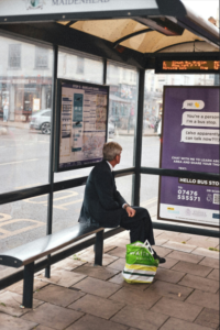 man waiting at a bus shelter