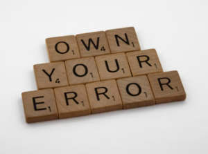 scrabble tiles spelling the phrase "own your error"