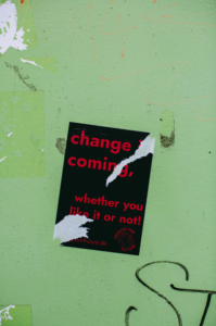 sticker on a wall with the phrase "change coming whether you like it or not"