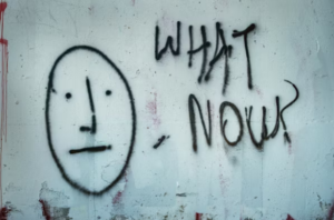 graffiti on a wall with a stick figure face and the words "what now?"